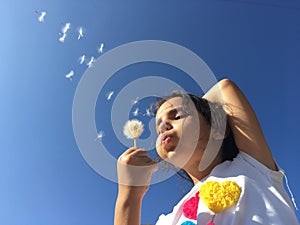 A little girl blowing dandelion seeds.