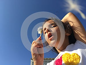 A little girl blowing dandelion seeds.