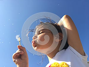 A little girl blowing dandelion seeds.