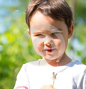 Little girl blowing the fluff off a dandelion head in spring