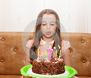 Little girl blowing out the candles on a birthday cake