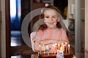 Little girl blowing out candles on a birthday cake on her birthday copy space