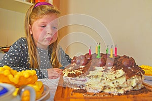 Little girl blowing out candles on her birthday cake. Small girl celebrating her six birthday. Birthday cake and little girl
