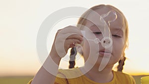 little girl blowing soap bubbles park. happy family. child kid daughter plays game outdoor. baby kid plays soap bubbles