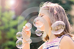 Little girl blowing soap bubbles in the park