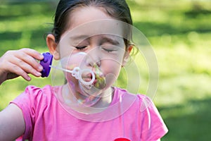 A little girl blowing soap bubbles in a park