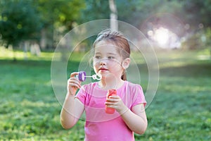 A little girl blowing soap bubbles in a park