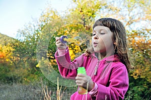 Little girl blowing soap bubbles to windward