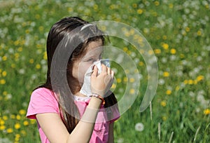 Little girl blows her nose with the handkerchief in the middle o