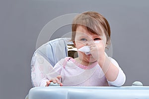 The little girl blows her nose into a paper handkerchief on grey background