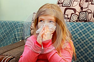 Little girl blows his nose in a paper tissue