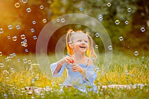 A little girl blows soap bubbles