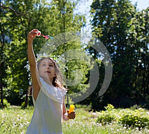 A little girl blows soap bubbles