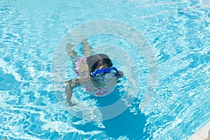 Little girl with blue diving glasses in an outdoor pool