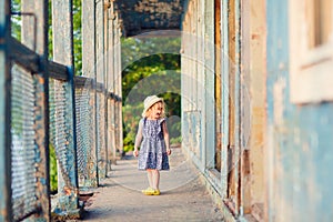 Little girl standing on porch of old ruined house.