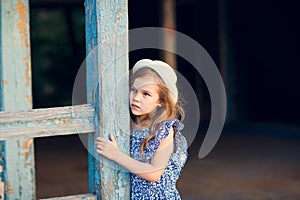 Little girl standing on porch of old ruined house.