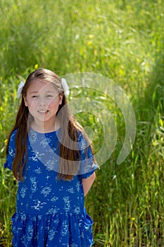 Little Girl in Blue Dress Smiling in Front of Field with Flowers