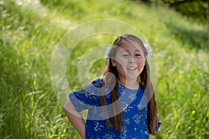Little Girl in Blue Dress Smiling in Front of Field with Flowers