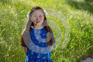 Little Girl in Blue Dress Smiling in Front of Field with Flowers