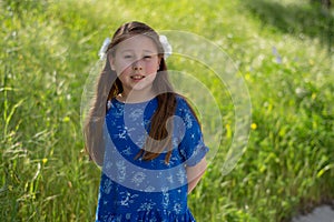 Little Girl in Blue Dress Smiling in Front of Field with Flowers