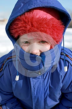a little girl in a blue winter jacket and in hood in frosty winter day. Top view