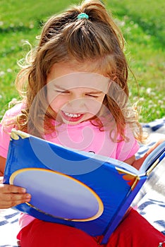 Little girl with a book in the garden