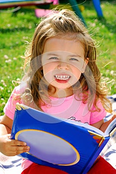 Little girl with a book in the garden