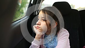 Little girl, bored in the car - looking out the window through the window - street reflection