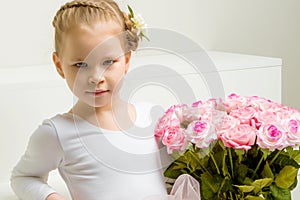 Little girl with a bouquet of flowers sits on a white staircase.