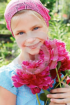 Little girl with a bouquet of pink peonies.