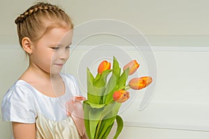 A little girl with a bouquet of tulips is sitting on the stairs.