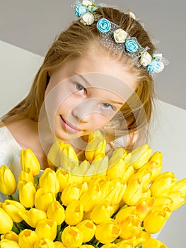 A little girl with a bouquet of tulips is sitting on the stairs.