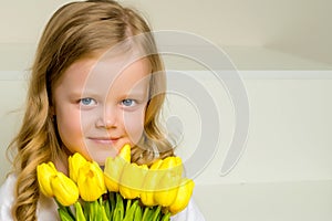 A little girl with a bouquet of tulips is sitting on the stairs.