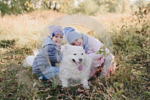 Little girl and boy in autumn on nature with a dog