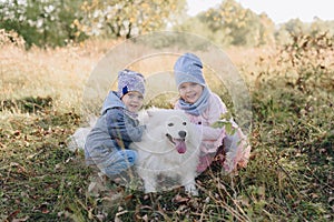 Little girl and boy in autumn on nature with a dog