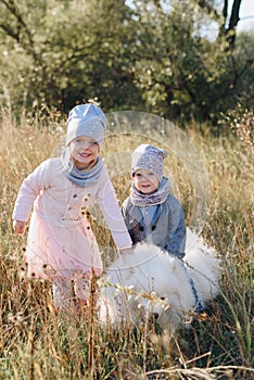 Little girl and boy in autumn on nature with a dog