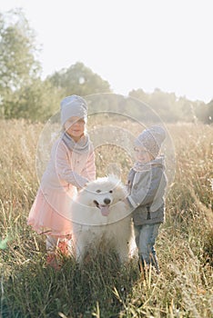 Little girl and boy in autumn on nature with a dog