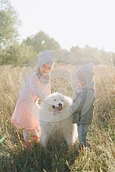 Little girl and boy in autumn on nature with a dog