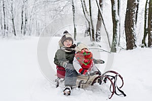 Little girl and boy enjoy a sleigh ride. Child sledding. Toddler kid riding a sledge. Children play outdoors in snow.