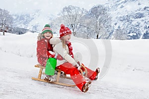 Little girl and boy enjoying sleigh ride. Child sledding. Toddler kid riding a sledge. Children play outdoors in snow. Kids sled