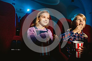 Little girl and boy watching a film at a movie theater