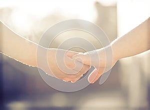 Little girl and boy hold hands close-up, against the backdrop of