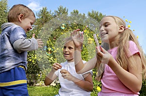 A little girl and a boy inflate soap bubbles for a joyful baby