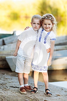 Little girl and boy playing on sunny summer day by the river.Happy kids sibling walking and playing water in the river