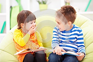 Little girl and boy reading and laughing
