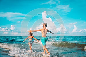 little girl and boy run and play with water at beach