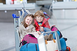 Little girl and boy sitting on suitcases on airport