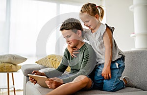 Little girl and boy watching video or playing games on their digital device tablet, smartphone.