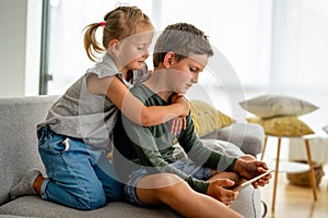 Little girl and boy watching video or playing games on their digital device tablet, smartphone.