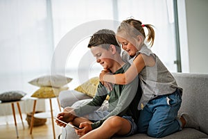 Little girl and boy watching video or playing games on their digital device tablet, smartphone.